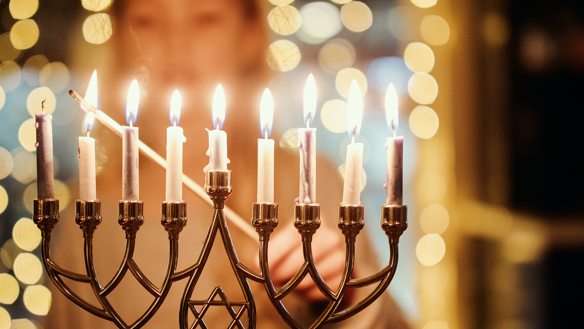 Image of young woman lighting Menorah